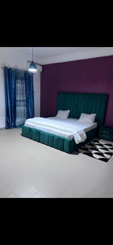 1 dormitorio con cama verde y pared morada en Joli appartement ngor / Almadies en Ngor
