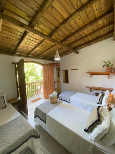 a bedroom with two beds and a balcony at Pousada Dendê Caraiva in Caraíva