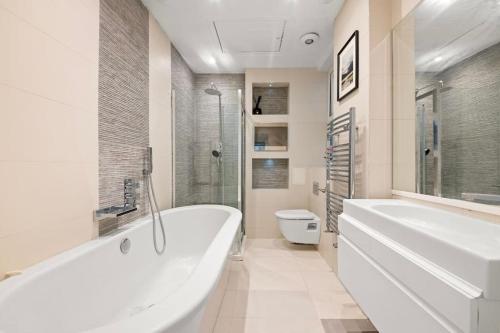 a white bathroom with a tub and a toilet at Knightsbridge Residence with Garden Terrace in London