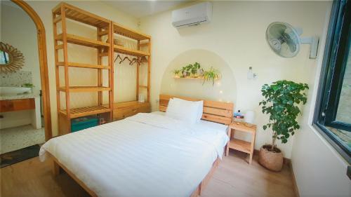a bedroom with a white bed and a plant at Dốc Chill - Villa gần Ba Vì, view núi, gần hồ, 40ph đi từ trung tâm Hà Nội in Hanoi
