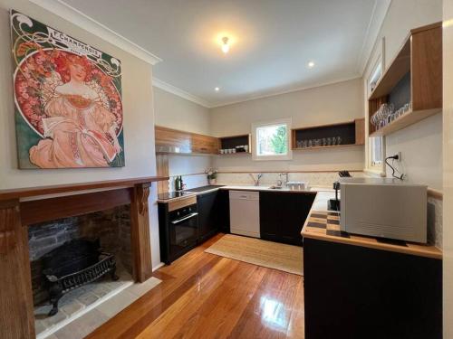 a kitchen with a fireplace with a painting on the wall at The Bank House in Mount Victoria