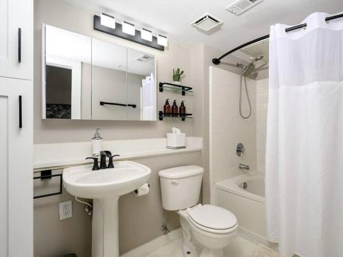 a white bathroom with a sink and a toilet and a mirror at Downtown Memphis Luxury Condo in Memphis