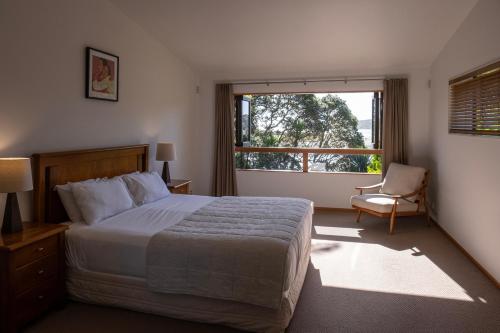 a bedroom with a bed and a window and a chair at Bow Street Apartments & Cottage in Raglan
