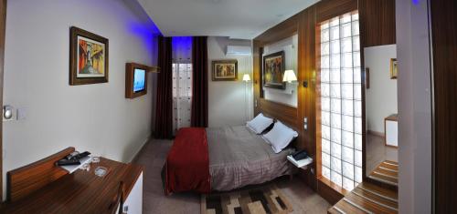 ein Schlafzimmer mit einem Bett und einem Schreibtisch in einem Zimmer in der Unterkunft Hôtel le convivial in Jijel