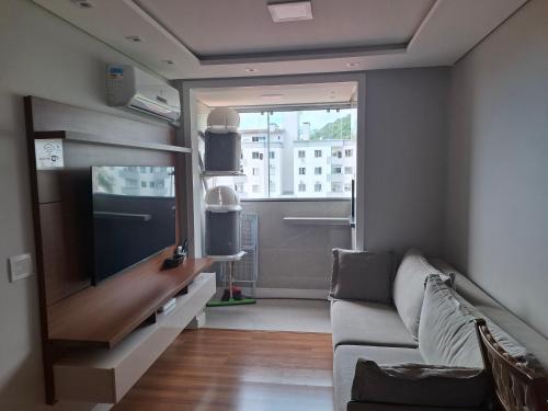 a living room with a couch and a flat screen tv at Casa 6 Encanto dos Mares in Itajaí