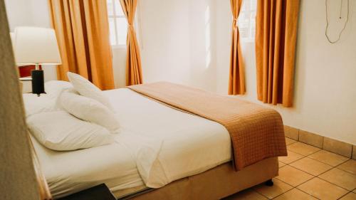 a bedroom with a bed with white sheets and pillows at Hotel Casa Amelia in Flores