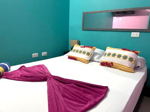 sypialnia z dużym białym łóżkiem z poduszkami w obiekcie La Viduka Hostel w mieście Cartagena de Indias