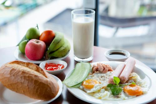 a table with a plate of breakfast food and a glass of milk at Carnival Villa in Da Lat
