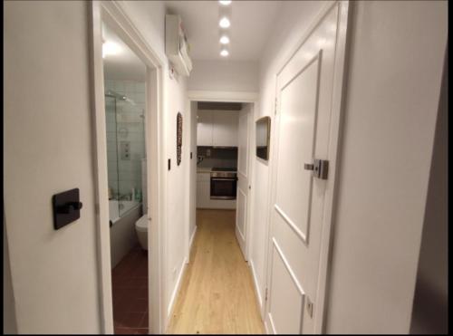 un couloir avec une porte blanche et une salle de bains. dans l'établissement Chapelstone, à Londres