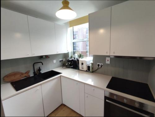 a kitchen with white cabinets and a sink and a window at Chapelstone in London