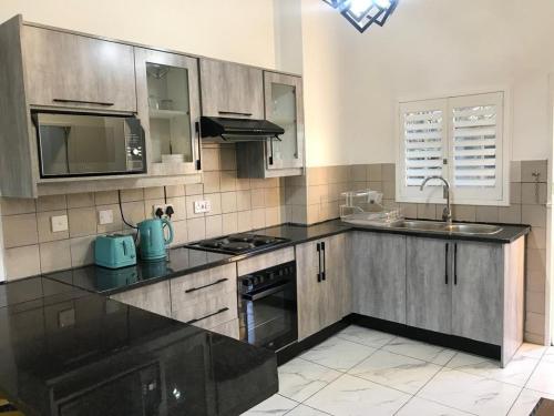a kitchen with a black counter top and a sink at Palm29 at Sunset Mews, Grand Palm - self catering appartment - Your Ideal Getaway for Work or Relaxation in Gaborone