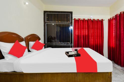 OYO Vibrant Inn في باتنا: غرفة نوم بسرير مع ستائر حمراء