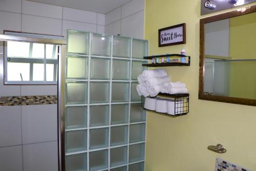 ein Bad mit einem Spiegel und Handtüchern an der Wand in der Unterkunft Hidden Gem Apartments (No.5) in Castries