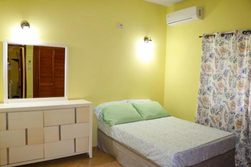 ein kleines Schlafzimmer mit einem Bett und einem Spiegel in der Unterkunft Hidden Gem Apartments (No.5) in Castries