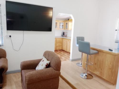 sala de estar con 2 sillas y TV de pantalla plana en Impeccable 2-Bed House in St Patrick's, en Celeste