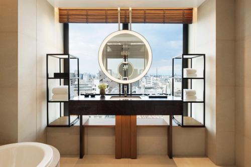 a bathroom with a mirror and a sink at TIAD, Autograph Collection in Nagoya