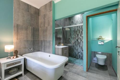 a bathroom with a tub and a sink and a toilet at Kelvin Maison's Haven in Johannesburg