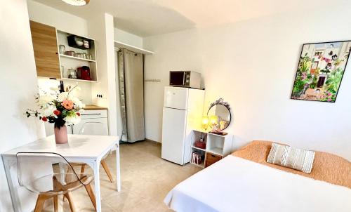 Il comprend une petite cuisine avec une table et un réfrigérateur blanc. dans l'établissement Le Cocon, à Gréoux-les-Bains