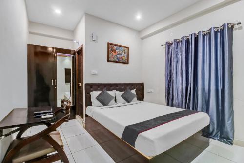 sypialnia z łóżkiem, biurkiem i zasłonami w obiekcie Collection O 1019 Galaxy Suites w mieście Hajdarabad