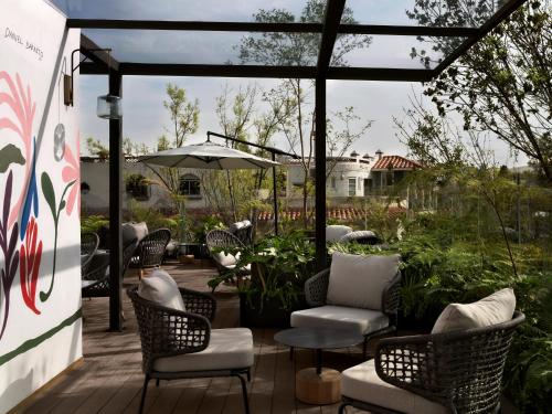 a patio with chairs and tables and an umbrella at Kimpton Virgilio in Mexico City