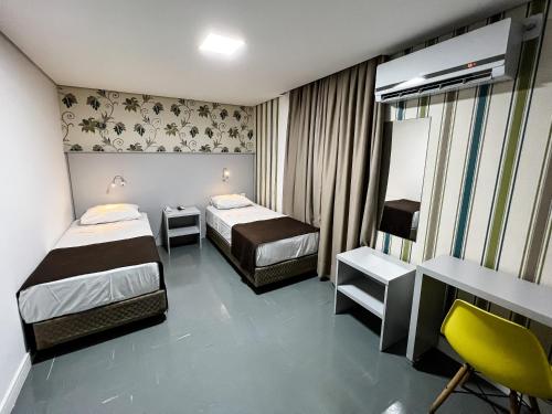 a hotel room with two beds and a desk at Life Hotel in Canoas