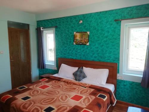 um quarto com uma cama com uma parede verde em queenhill homestay2 em Ooty