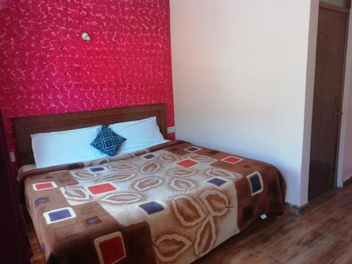 um quarto com uma cama com uma parede vermelha em queenhill homestay2 em Ooty
