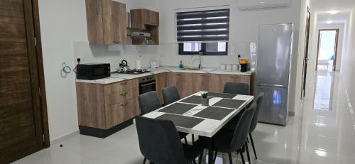una cucina con tavolo, sedie e frigorifero di Green Valley Flats a Żebbuġ