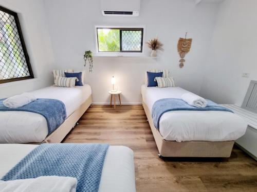 a room with three beds and a window at Holiday on Hibiscus in Urangan