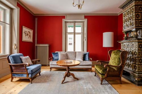 a living room with red walls and a table and chairs at Villa Klainguti in Pontresina
