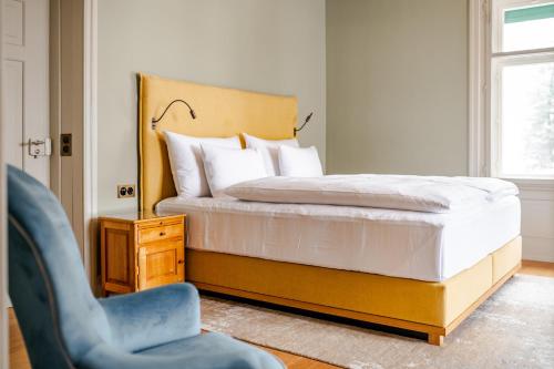 a bedroom with a bed and a blue chair at Villa Klainguti in Pontresina