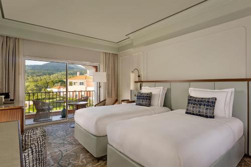 a hotel room with two beds and a balcony at Penha Longa Resort in Sintra