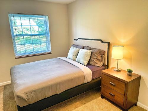 a bedroom with a bed with a nightstand and a window at 2BR Heritage Hill Apt Long Stay Discount in Grand Rapids