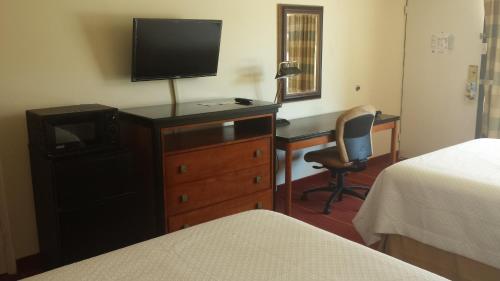 a hotel room with a desk and a television on a dresser at Rodeway Inn & Suites Greensboro Southeast in Greensboro
