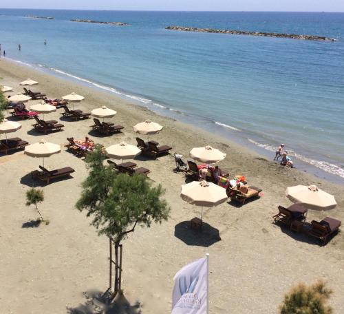 a beach filled with lots of umbrellas on a sunny day at Olympic Residence Deluxe Apartments in Limassol