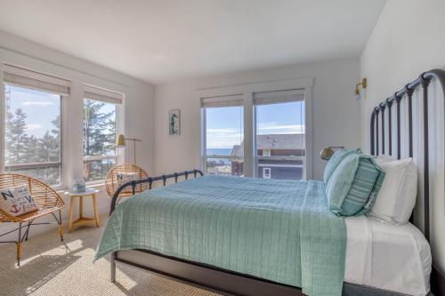 a bedroom with a bed with a green comforter and windows at After Dune Delight in Lincoln City