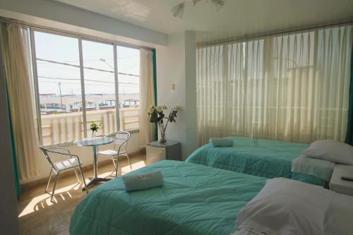 a hotel room with two beds and a table and a window at El Gamonal - Paracas in Paracas