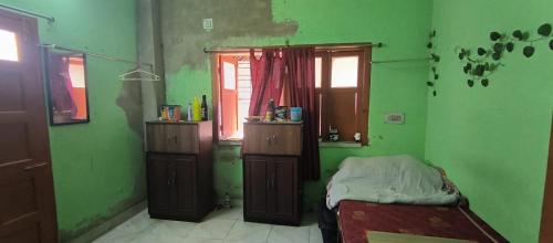 Grünes Zimmer mit einem Bett und einem Fenster in der Unterkunft Ladies pg in Kalkutta