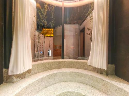 a large bath tub in a room with curtains at 云缦·兮温泉民宿 in Xinzhou