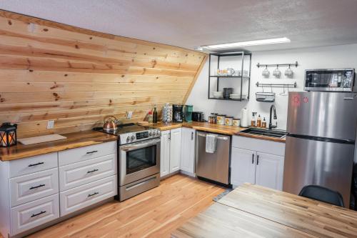 a kitchen with white cabinets and a wooden wall at A-Frame Cabin - Mountain Views, Deck, Pet Friendly in Idaho Springs