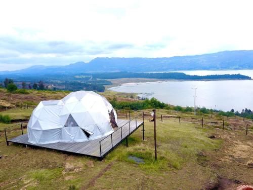 a white tent on top of a hill next to a lake at Lujoso Glamping MarQua Spa Guatavita Wifi Cocina in Guatavita