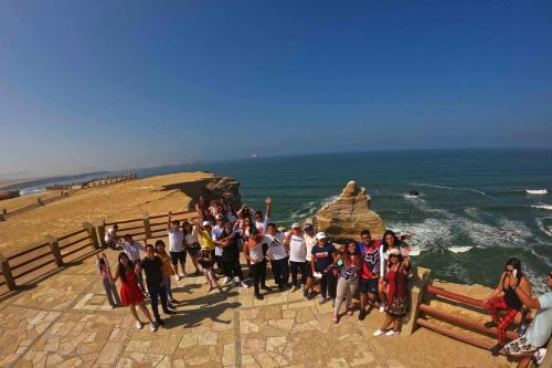 a group of people posing for a picture at the ocean at El Gamonal - Paracas in Paracas