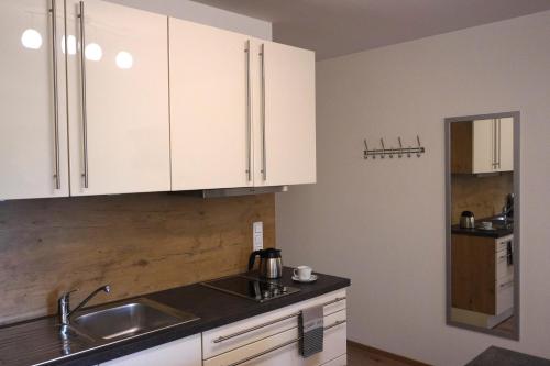 uma cozinha com armários brancos e um lavatório em Ferienwohnung Am Feldbach em Bad Aibling