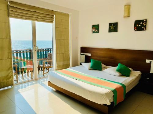 a bedroom with a bed and a balcony with the ocean at Saprin Beach By Travel Corners in Uswetakeiyawa