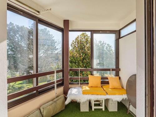 un balcon avec deux chaises jaunes rembourrées et des fenêtres dans l'établissement Appartement à Anglet : proche commerces, plages, et nature, avec parking et loggia - FR-1-3-606, à Anglet