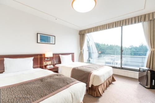 2 letti in una camera d'albergo con una grande finestra di Rembrandt Premium Fuji Gotenba a Gotemba