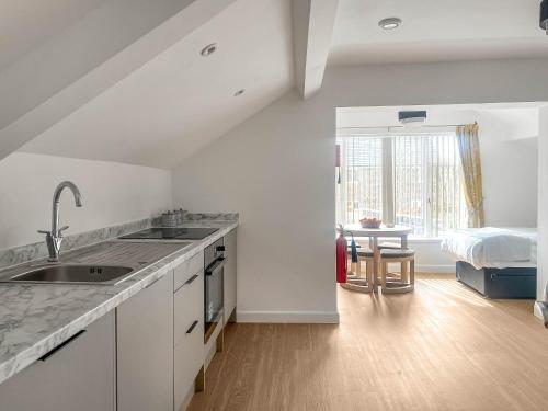 a white kitchen with a sink and a bedroom at Highmead - Uk46951 in Blackwood