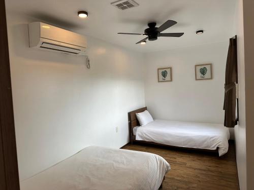 a bedroom with two beds and a ceiling fan at サザンメモリ今帰仁 in Nakijin