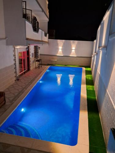 a swimming pool with blue water in a building at Villa belle vue in Boumaʼchouk