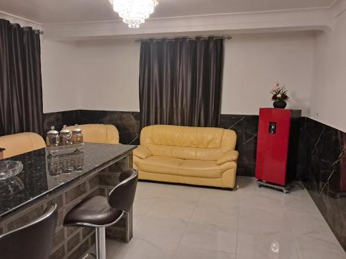 a waiting room with a yellow couch and a red refrigerator at Villa belle vue in Boumaʼchouk